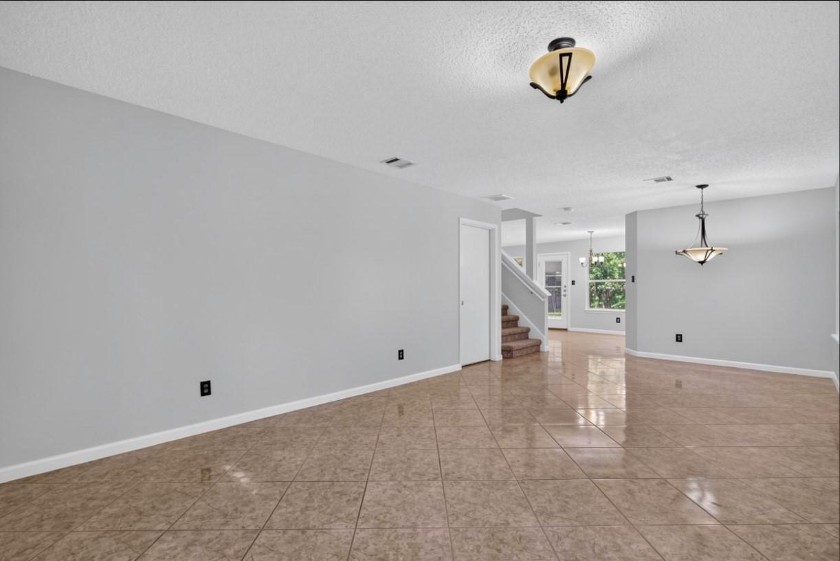 Open living and dining area with glossy tan tile floors and a staircase.
