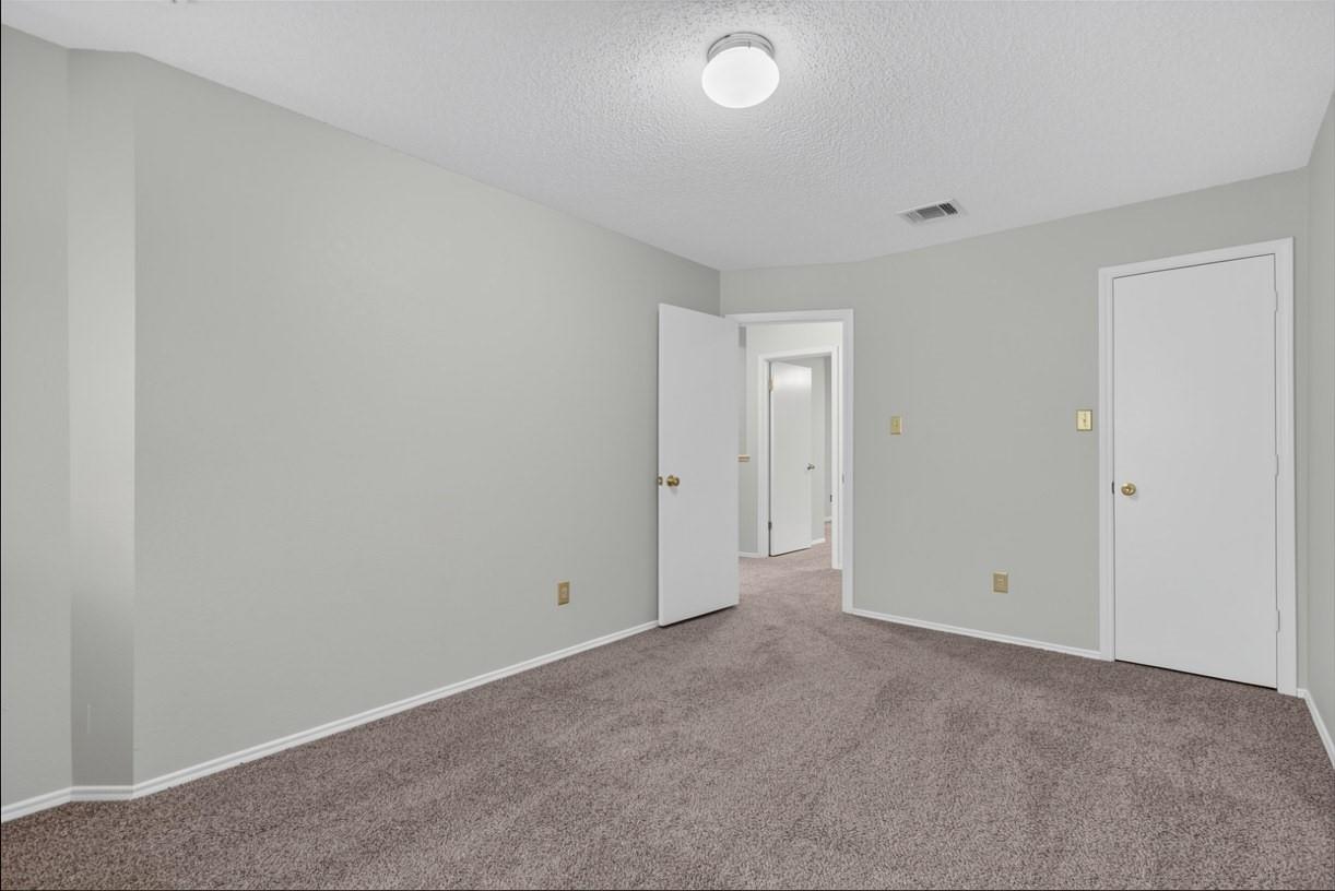 Empty bedroom with mauve carpet, a closet door, and an open doorway to the hall.