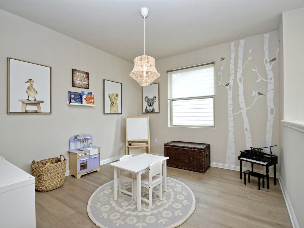 Playroom with a child-sized table, toy kitchen, toy piano, and birch-tree wall decals.