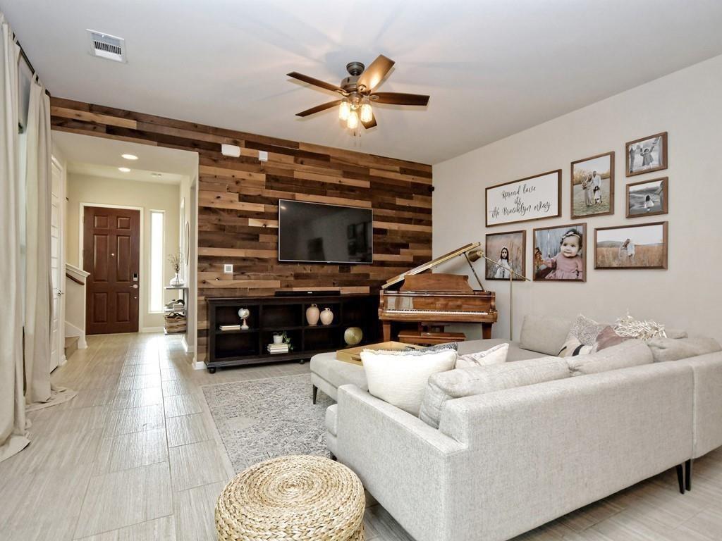 Living room with a reclaimed wood TV wall, piano, and light sectional sofa.