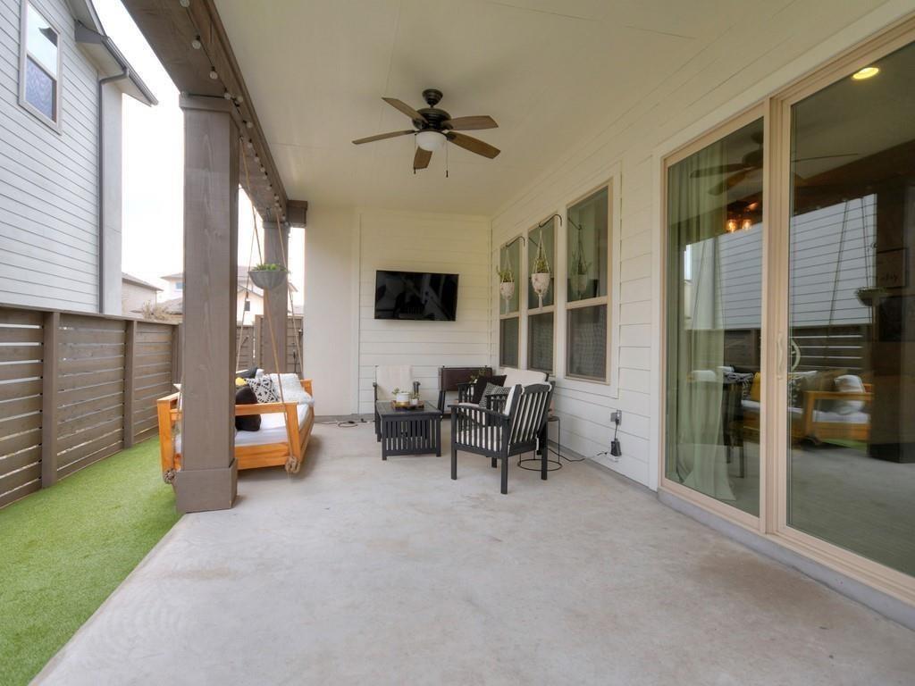 Covered patio with a wooden hanging swing, black chairs, ceiling fan, and sliding glass doors.