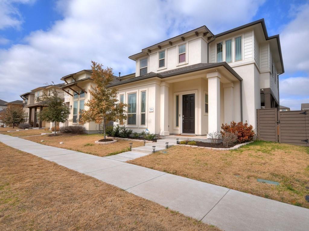 Two-story attached home with a covered entry, dark front door, and front walkway.