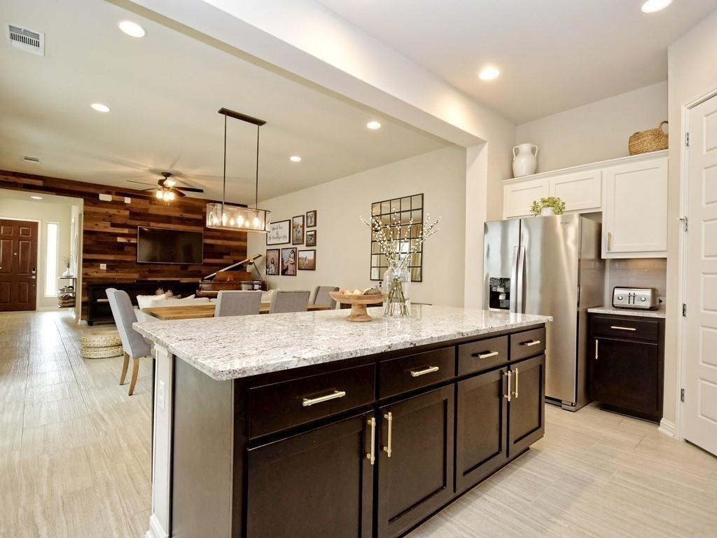 Open-plan kitchen with a large granite island, dark cabinets, and a reclaimed-wood living room accent wall.