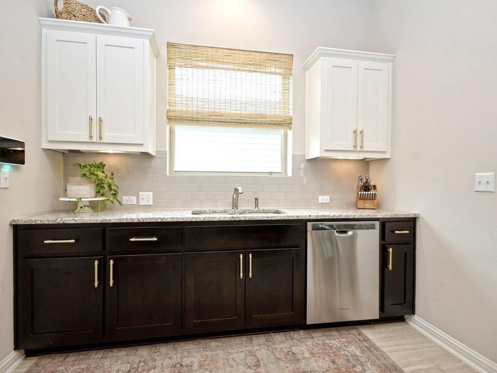 Kitchen with dark cabinets, granite counters, white tile backsplash, and stainless steel dishwasher.