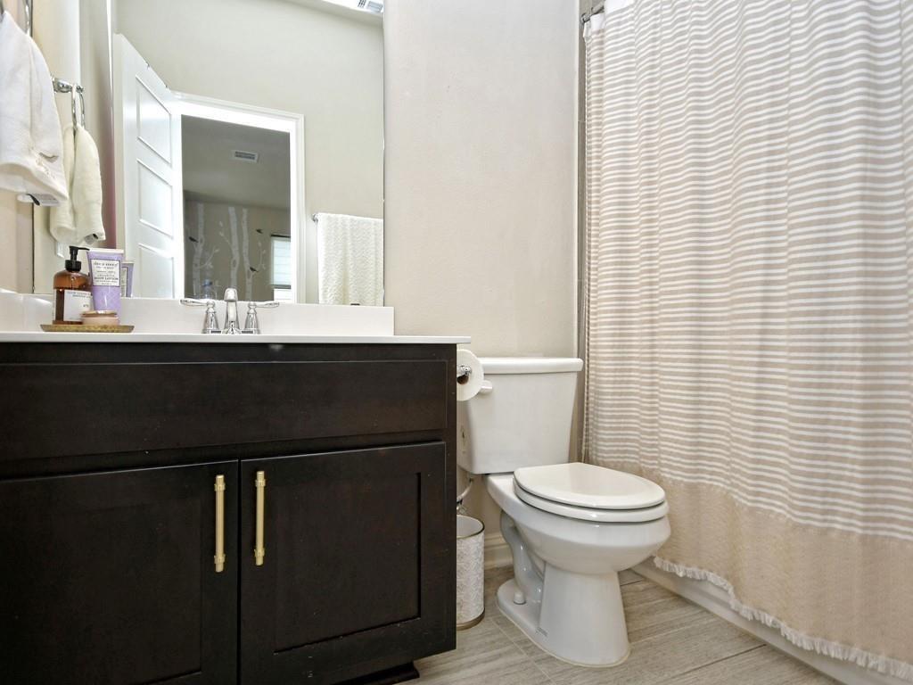 Bathroom with a dark vanity, white sink, toilet, and striped shower curtain.