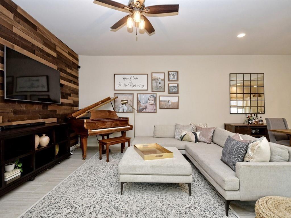 Living room with a gray sectional, wooden piano, and dark wood-plank accent wall.