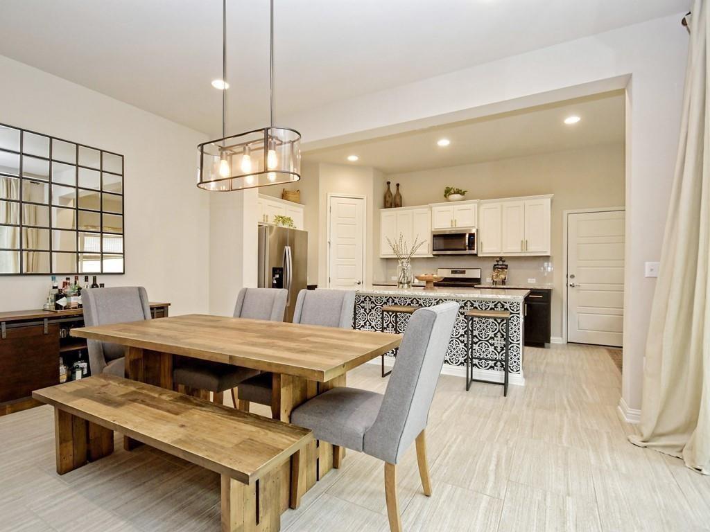 Open dining area with a rustic wood table and bench beside a kitchen with a patterned island.