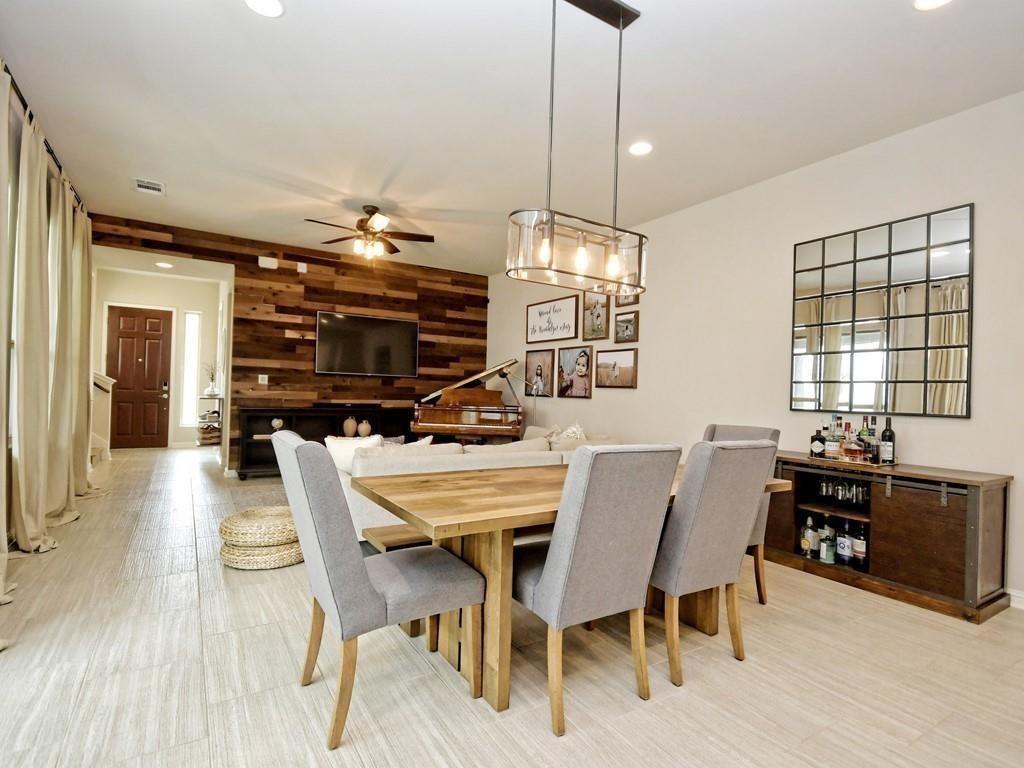 Open-plan dining area with a wooden table, gray chairs, and a rustic wood accent wall.
