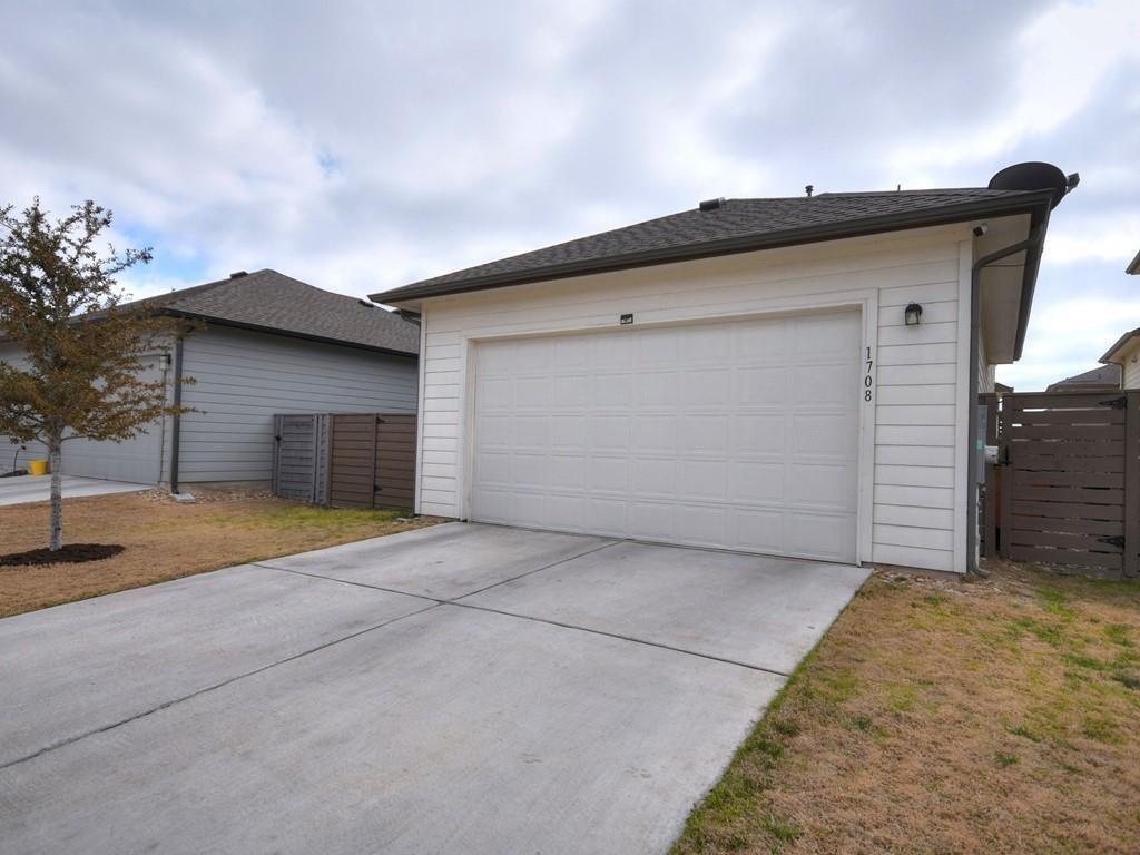 White-sided structure with a double garage door and broad concrete driveway.