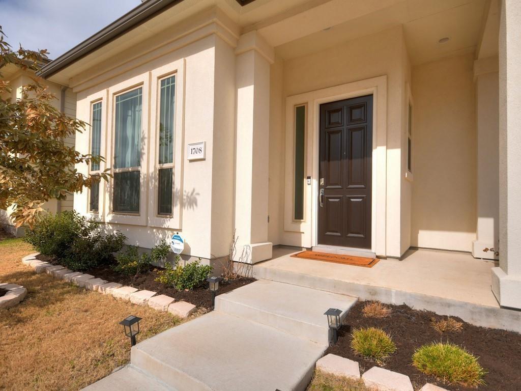 Home entrance with dark paneled door, tall windows, and a landscaped walkway.