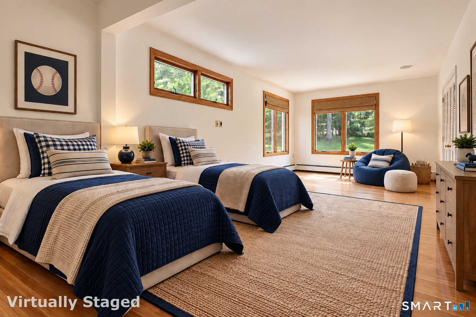 Virtually staged bedroom with twin beds, hardwood floors, large windows, and a blue lounge chair.