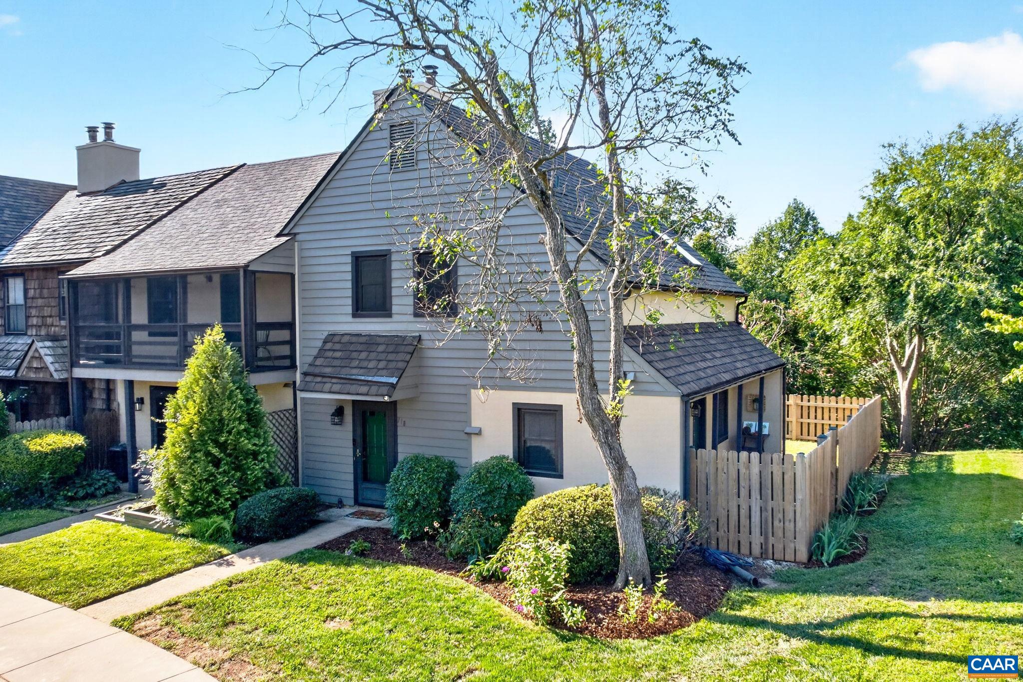 Gray-sided home with screened porch, green front door, and fenced landscaped yard.