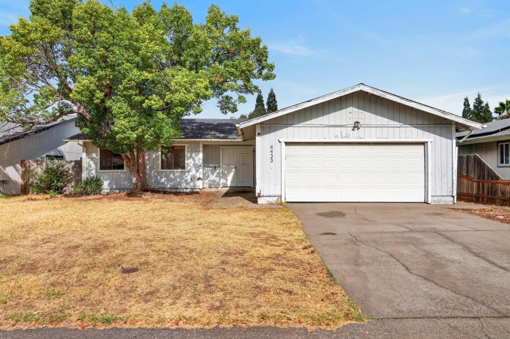 Single-story home with a large attached garage, wide driveway, and mature tree in the front yard.