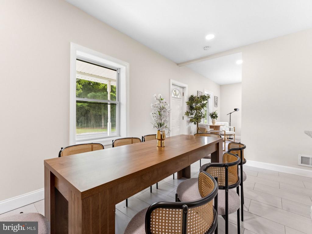 Furnished dining room with a long wooden table and cane-back chairs beside a window.