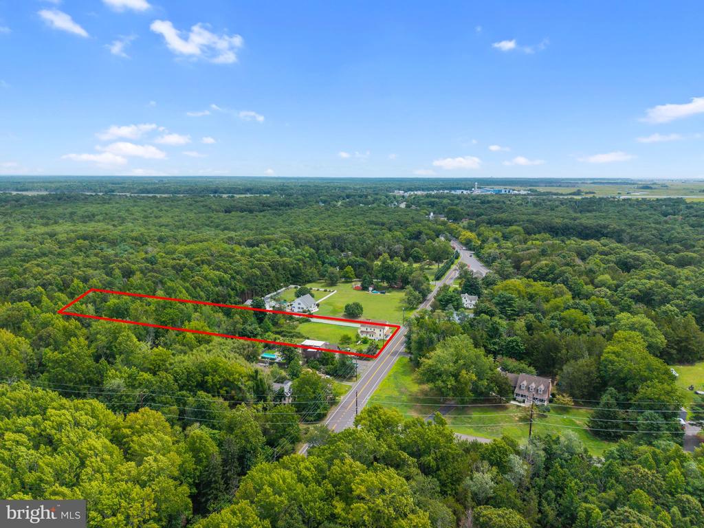 Aerial view of a wooded parcel outlined in red beside Route 542, with homes and open lawns nearby.