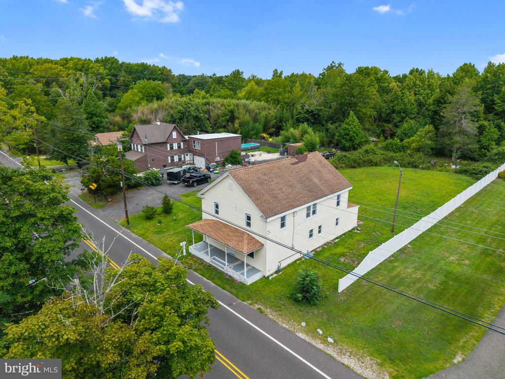 Aerial view of a cream-colored house beside Route 542, with a large fenced lawn and wooded surroundings.