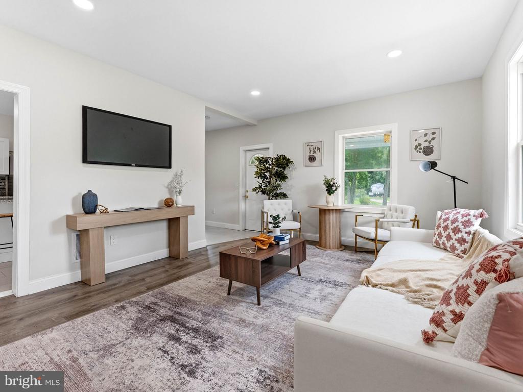 Staged living room with a white sofa, patterned rug, and wall-mounted television.