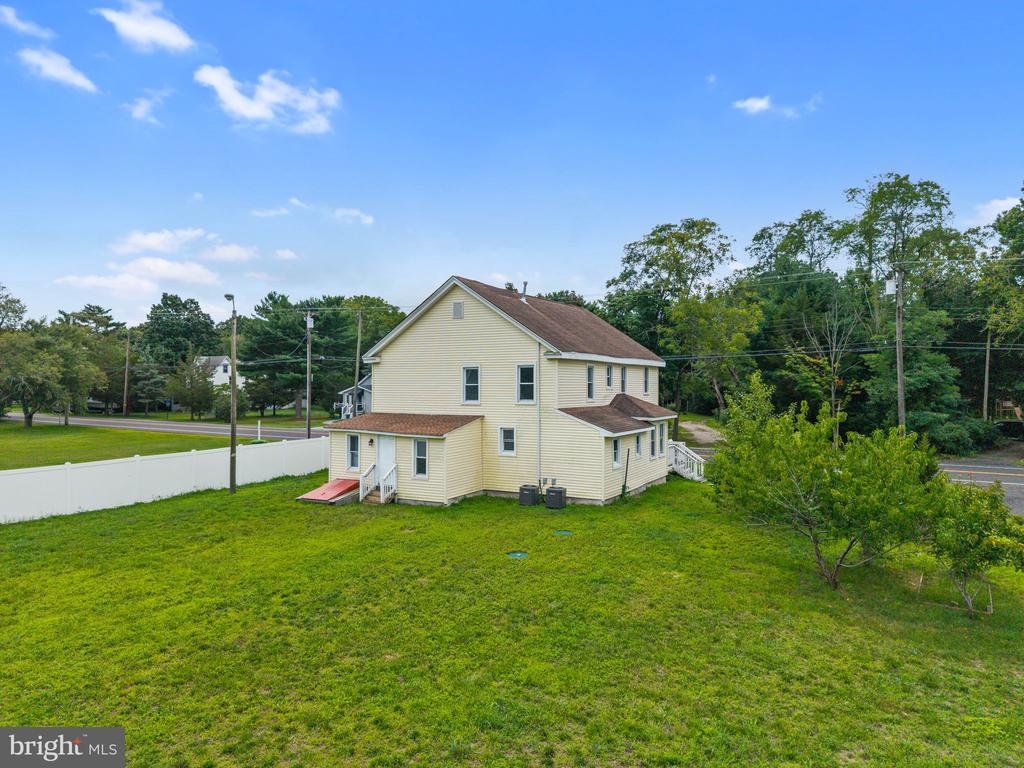 Pale yellow two-story house with multiple additions in a spacious grassy yard.