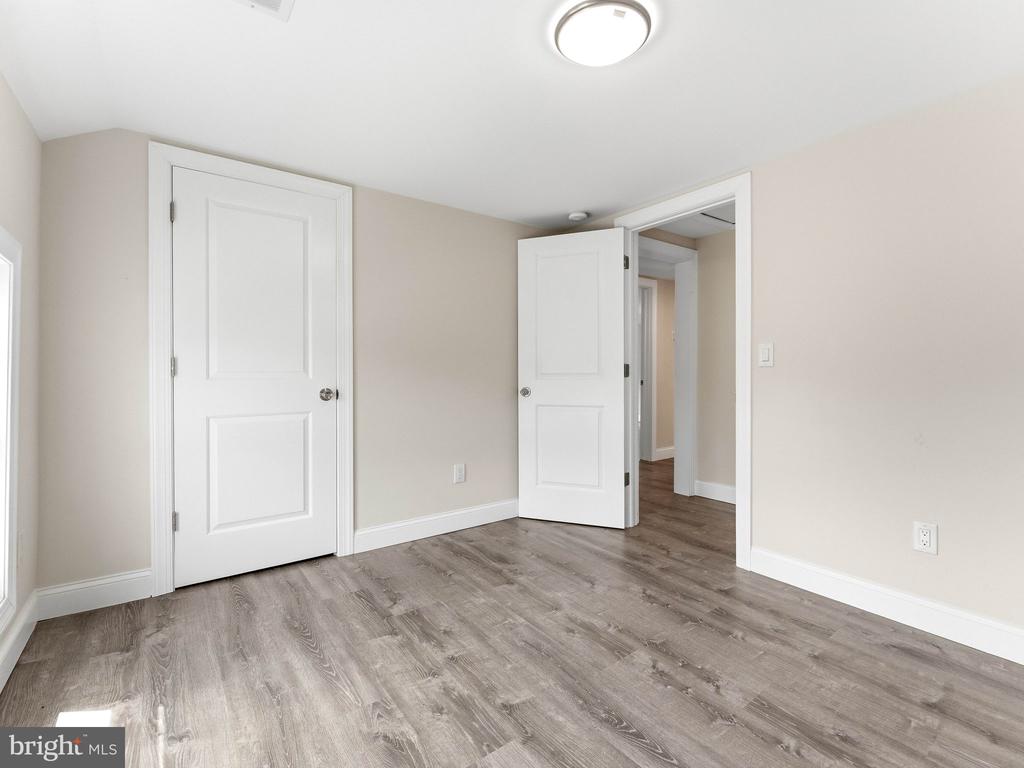 Empty room with gray wood-look flooring, neutral walls, and two white doors.