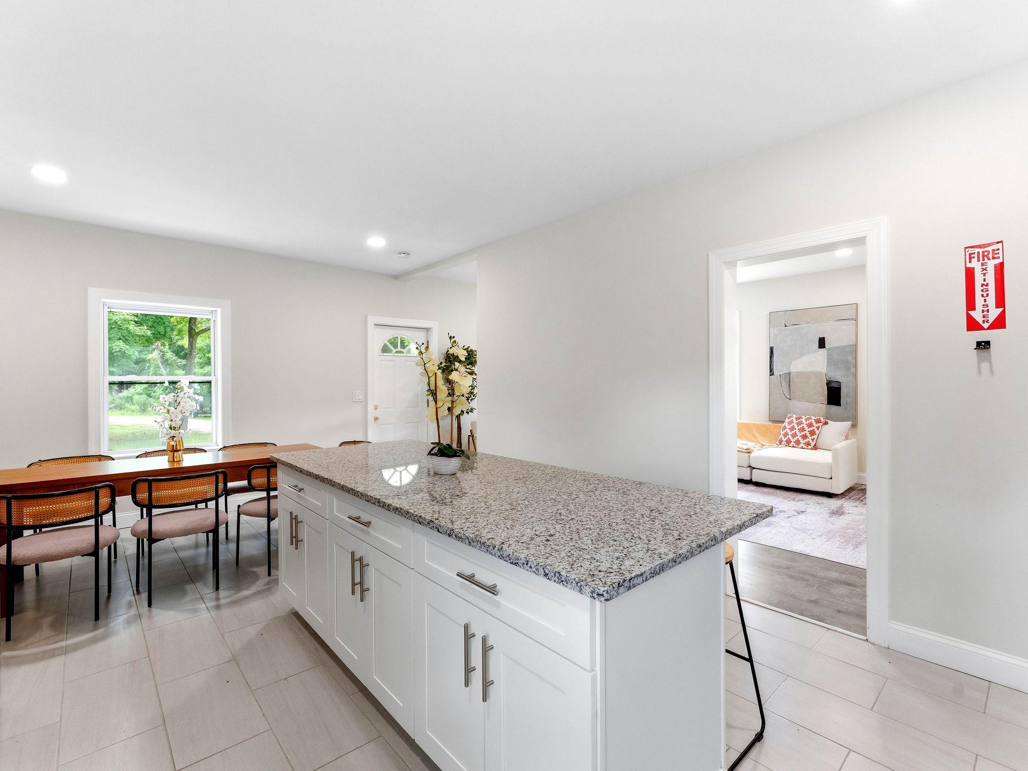 Kitchen with a large granite island, white cabinets, and an adjoining dining area.