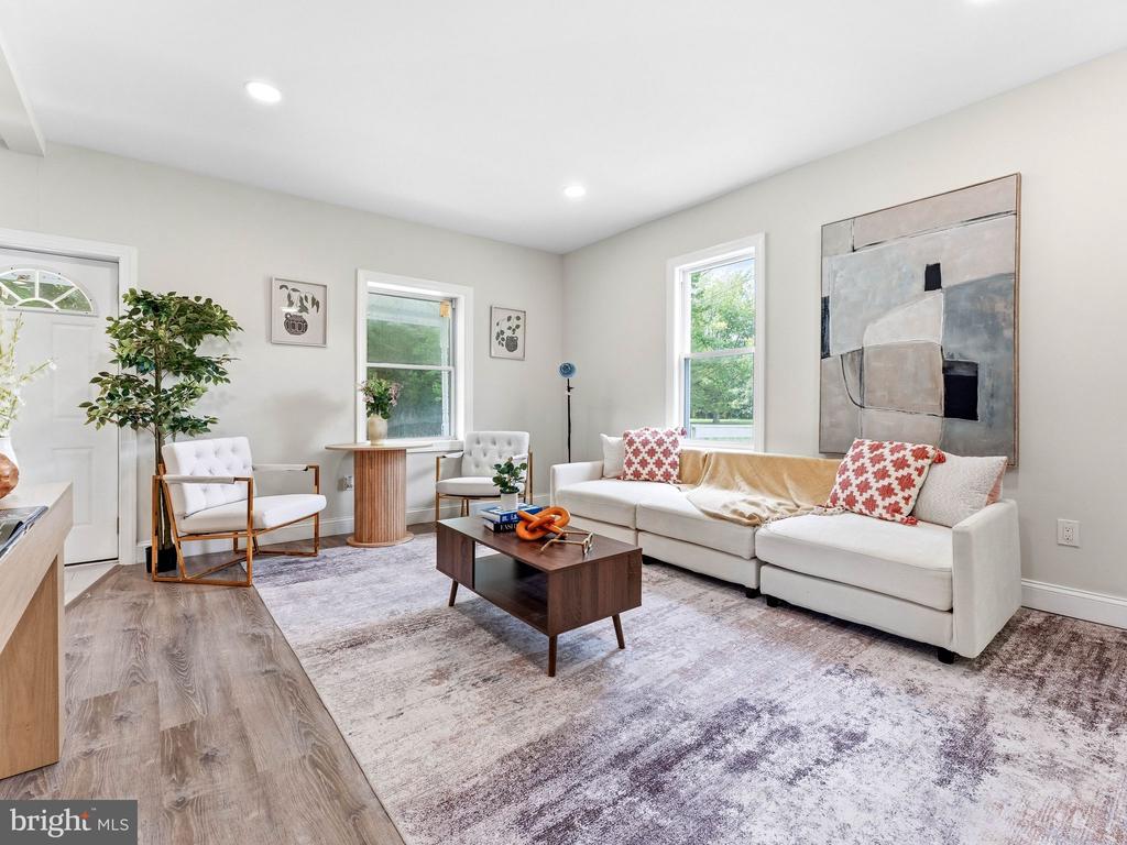 Furnished living room with a white sectional, accent chairs, and large abstract wall art.