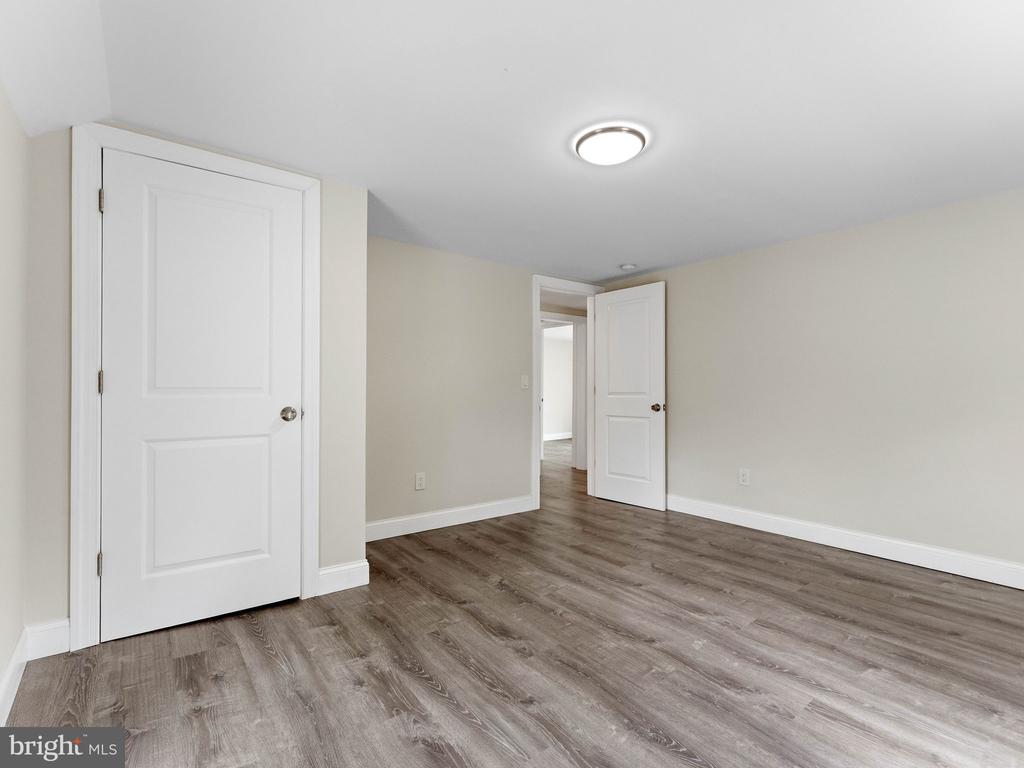 Vacant room with gray wood-look flooring and two white doors.