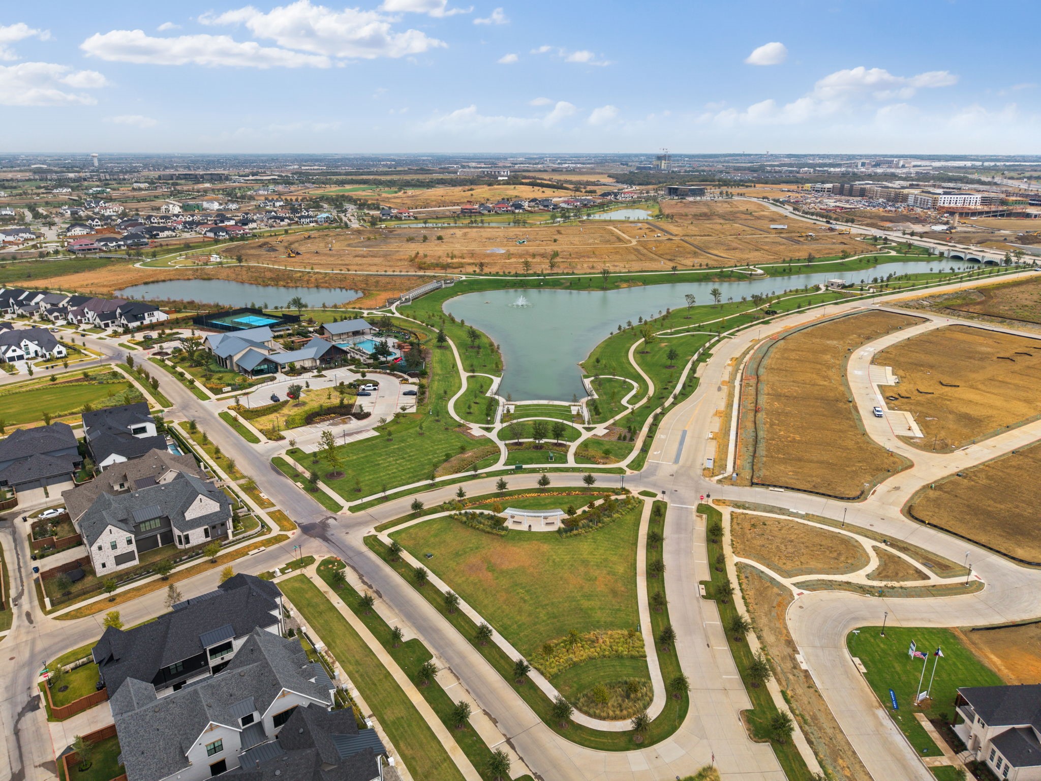 Aerial view of a neighborhood park with a lake, walking paths, and nearby homes.