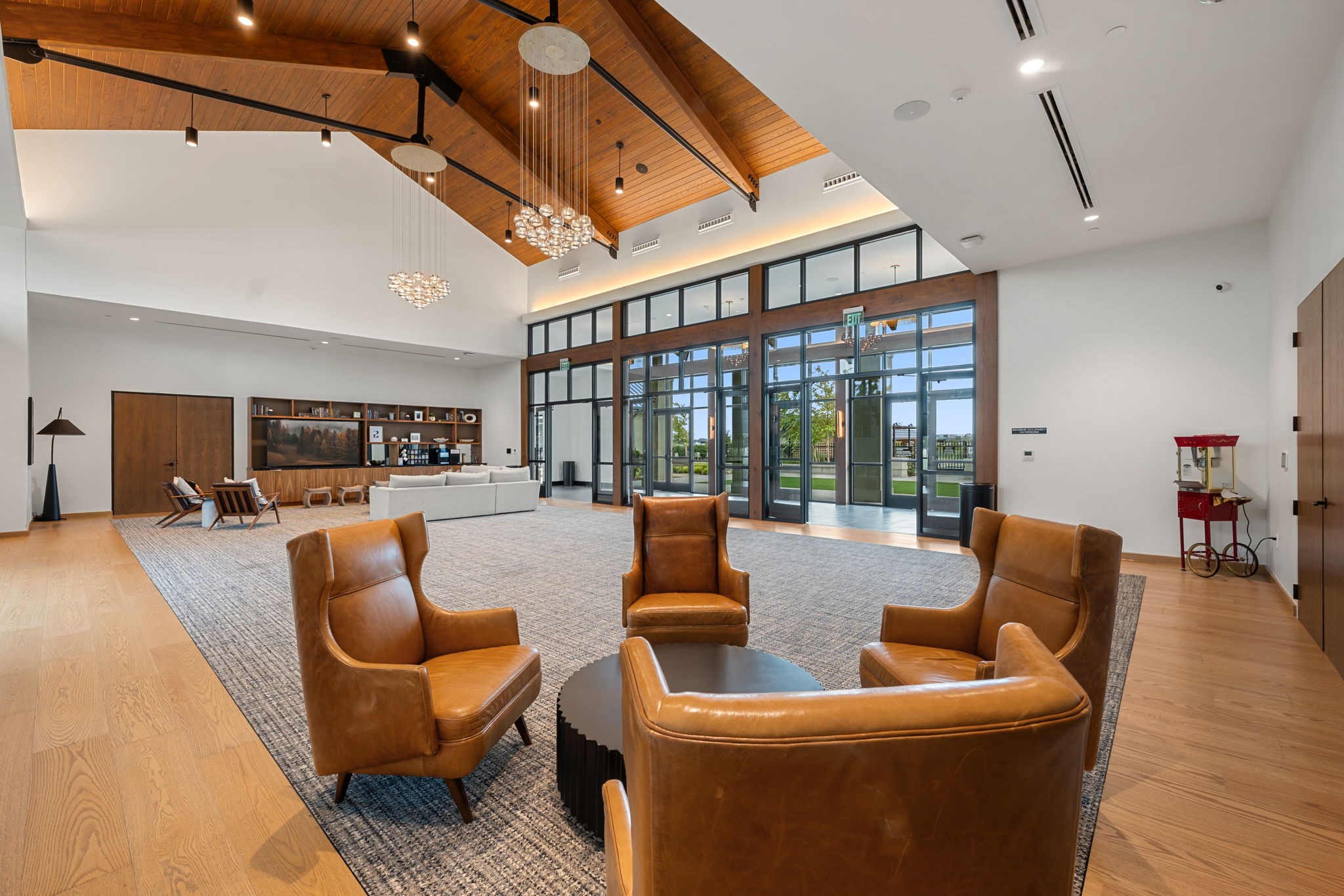 Communal lounge with leather armchairs, vaulted wood ceiling, and floor-to-ceiling glass doors.