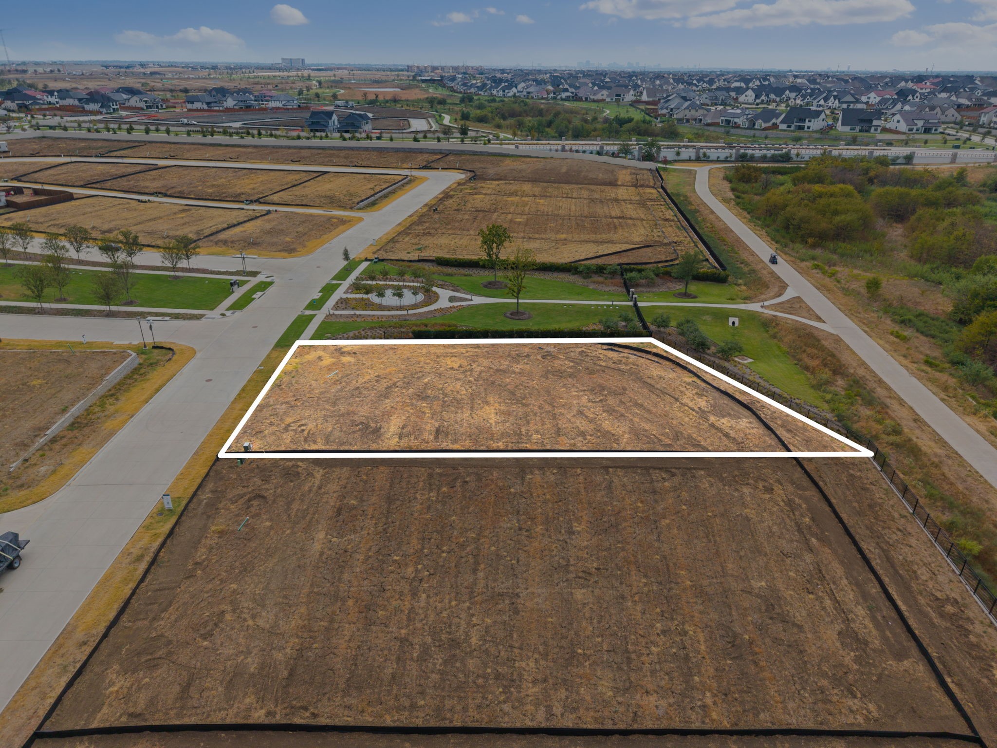 Vacant lot outlined in white among neighborhood roads and homes.