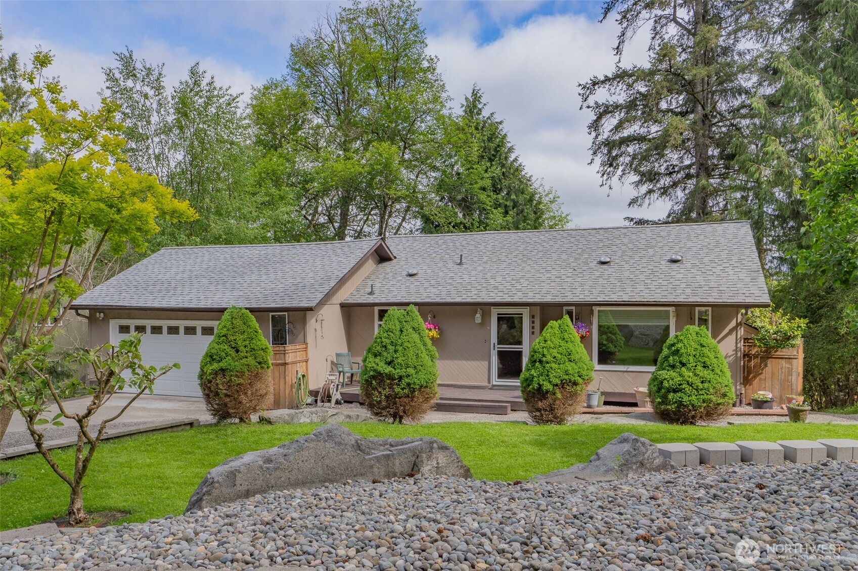 Single-story taupe house with an attached garage, front porch, and landscaped rock garden.