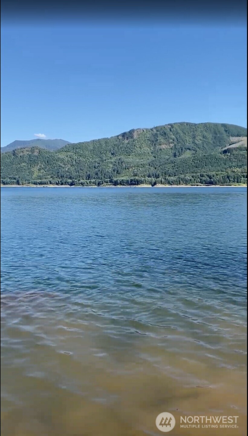 Blue water stretches toward a forested shoreline and green hills.
