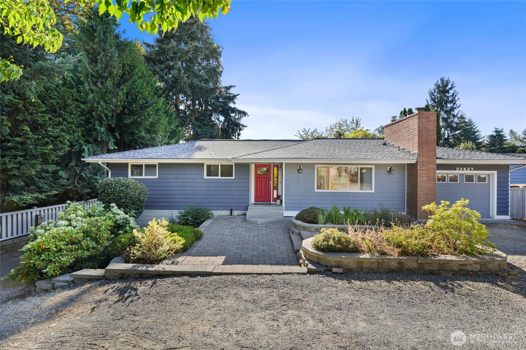 Blue single-story house with a red front door, brick chimney, and landscaped walkway.