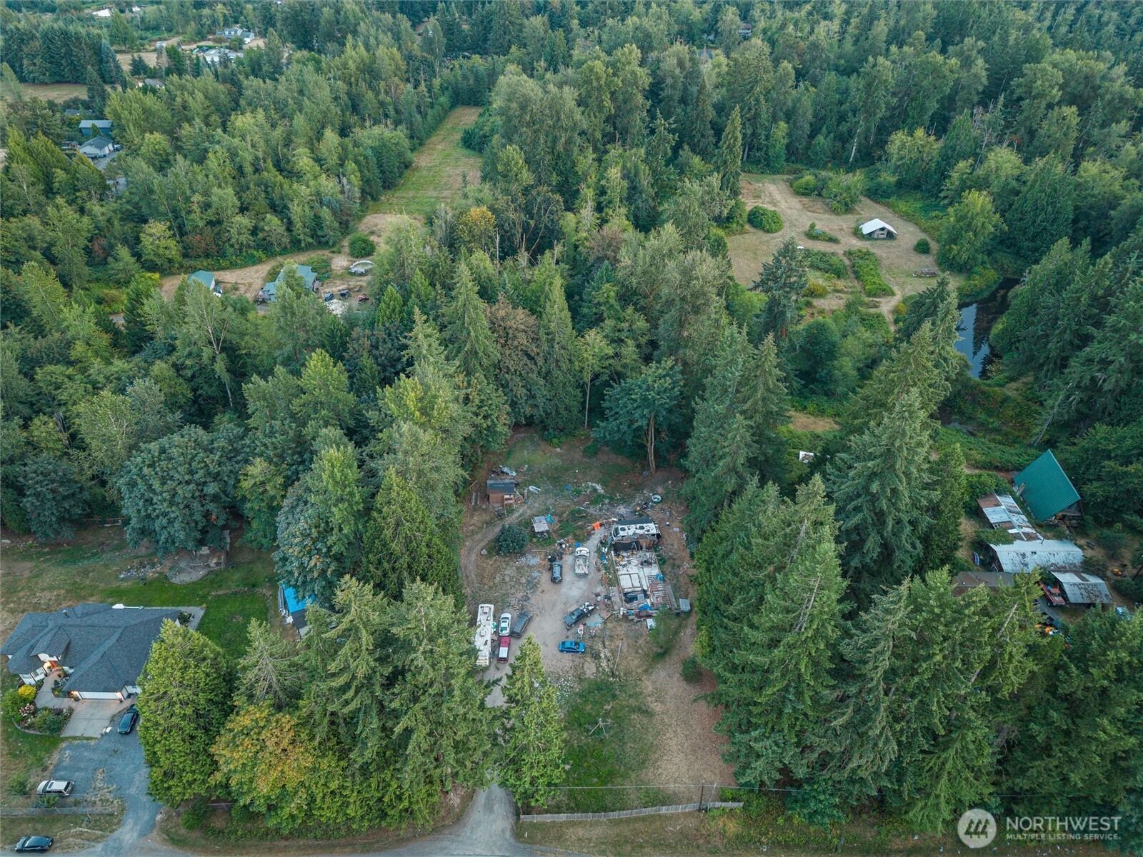 Aerial view of a wooded property with a clearing and partially built structure.