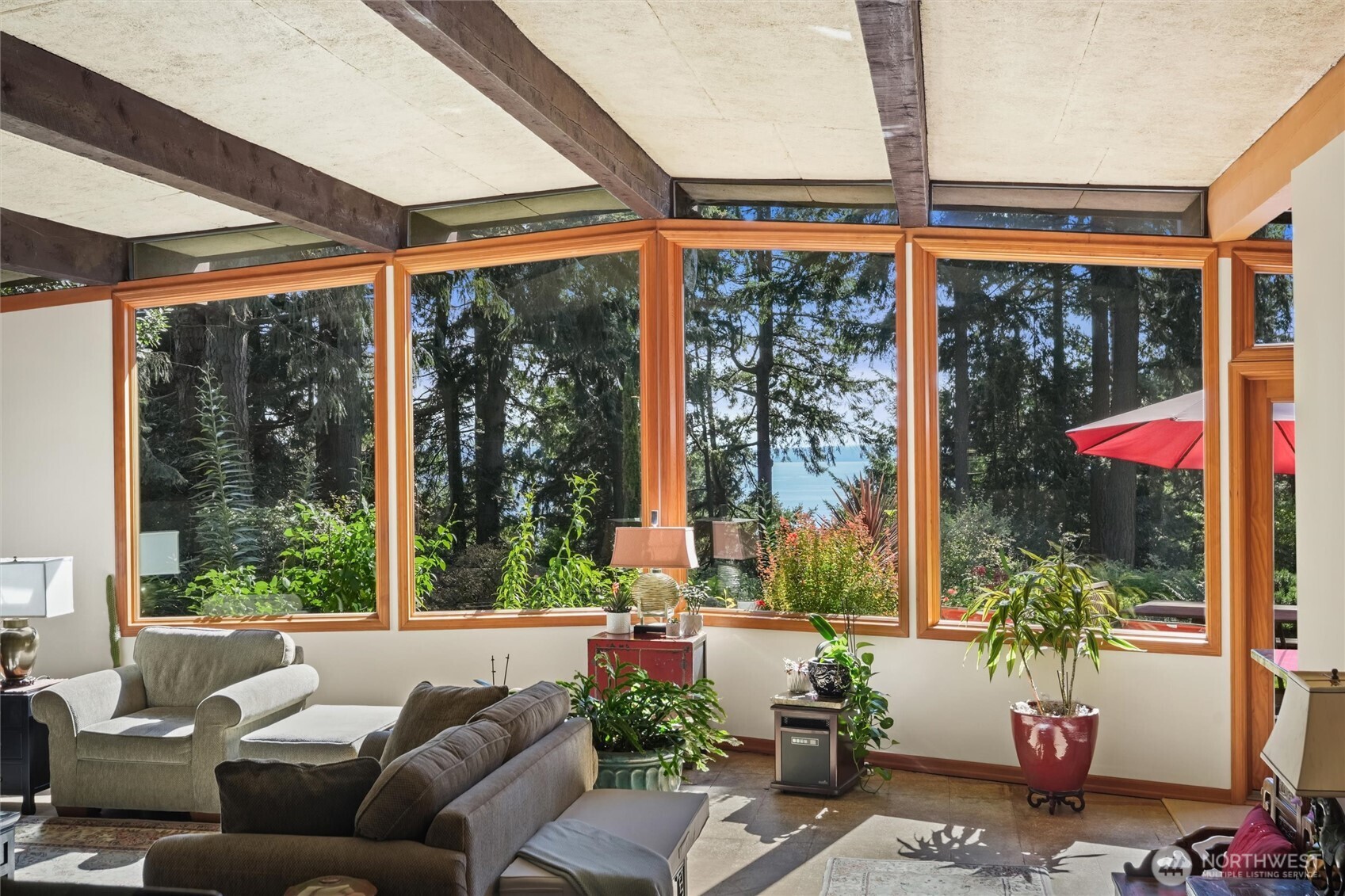 Living room with expansive wood-trimmed windows overlooking trees and water.