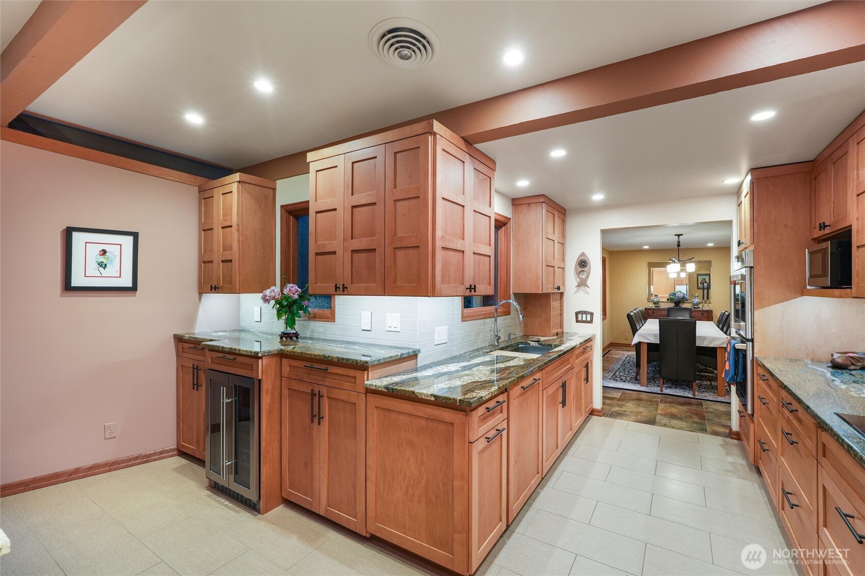 Kitchen with warm wood cabinets and granite counters, opening to a dining room.