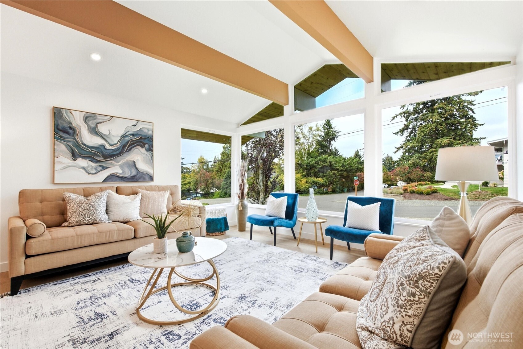 Staged living room with vaulted ceilings, exposed beams, and large windows.