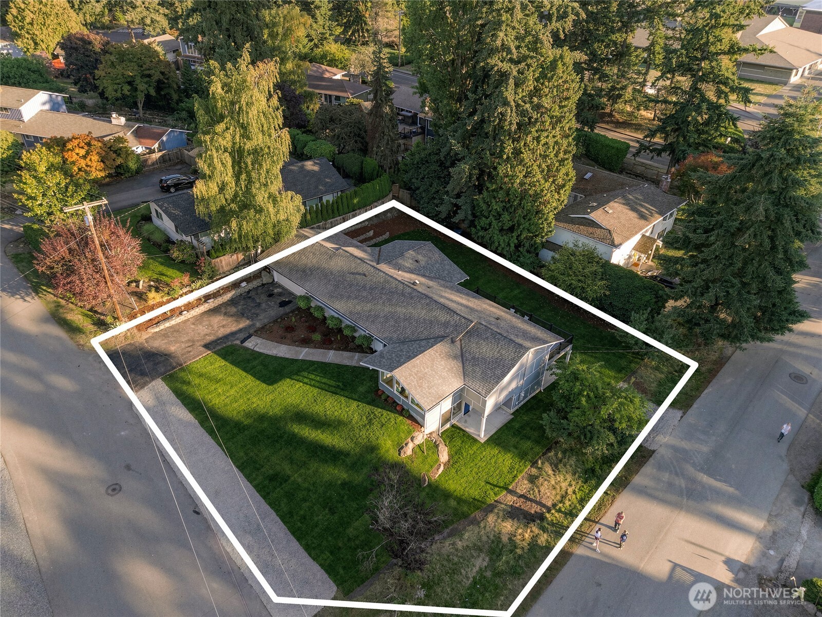Aerial view of a single-story house and its tree-lined lot, outlined in white.