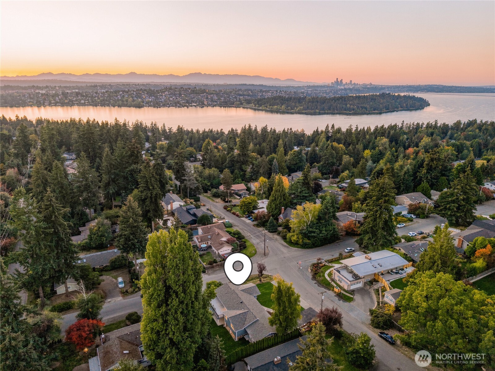 Aerial neighborhood view toward Lake Washington, with Seattle’s skyline and mountains in the distance.