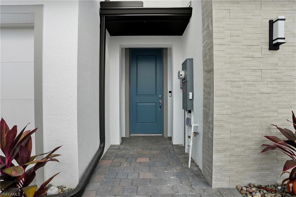 Covered home entry with a blue front door, stone pavers, and light stone veneer.