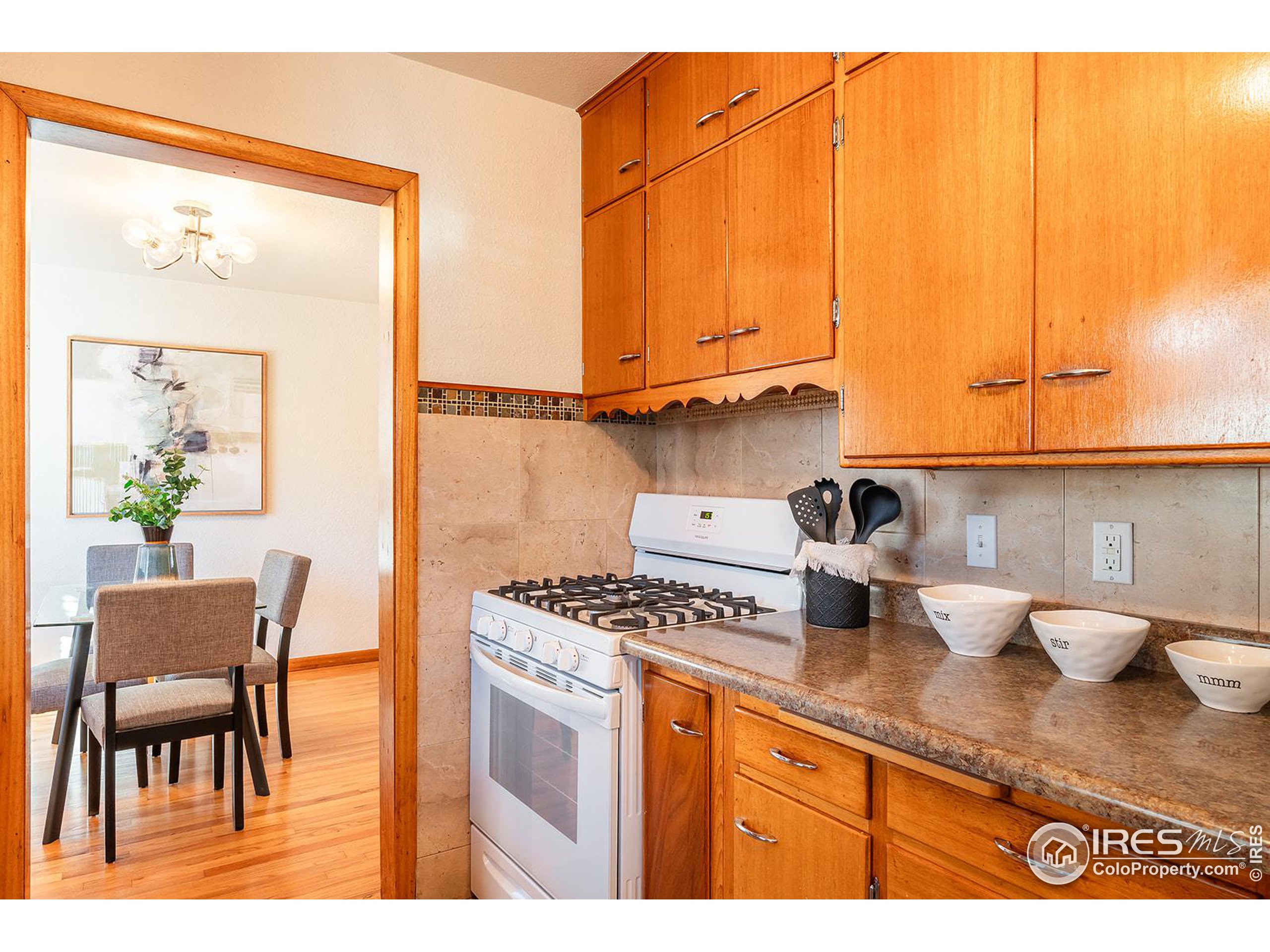Kitchen with warm wood cabinets and a gas range opening onto a dining area.