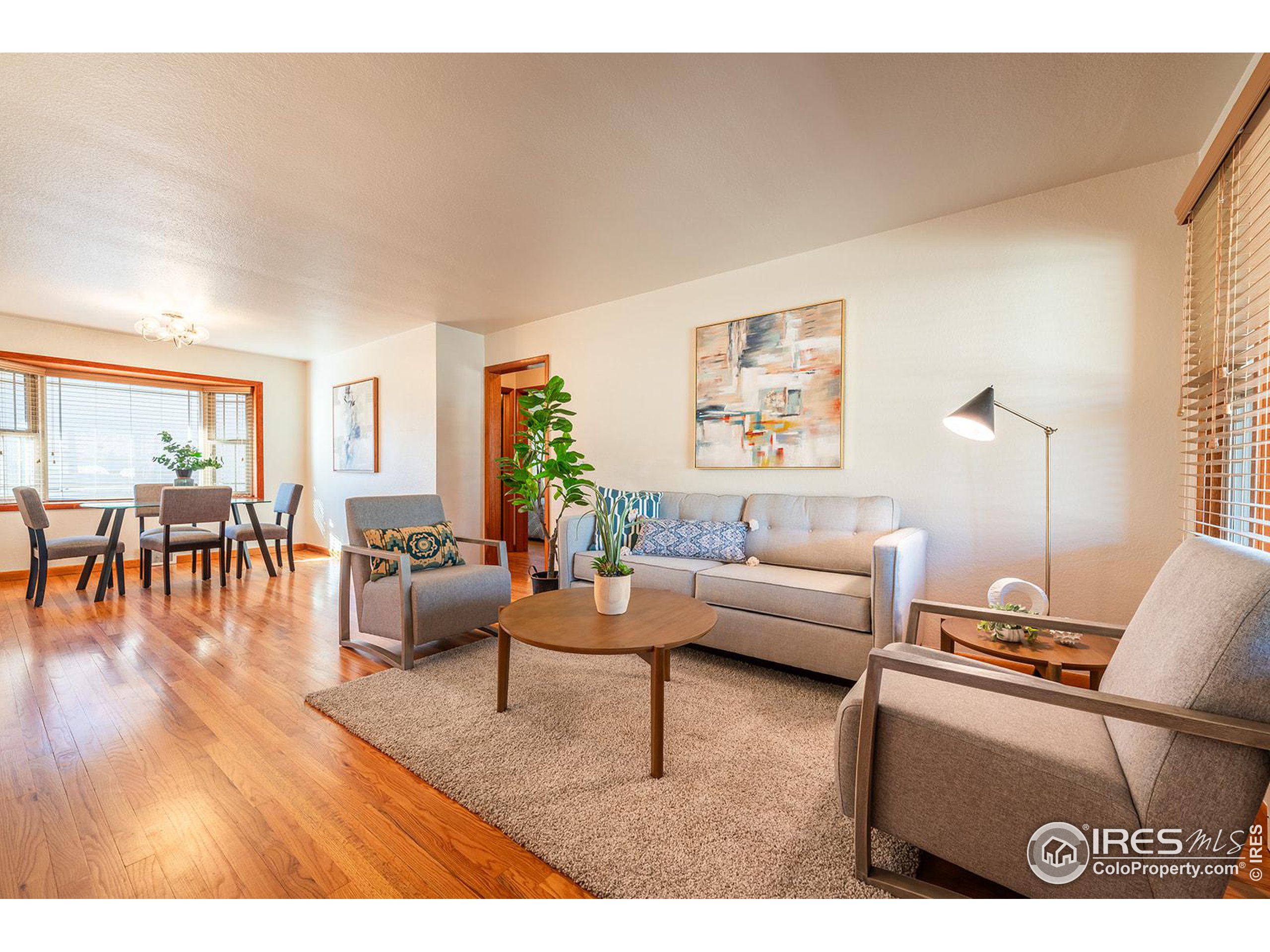 Staged living room with gray seating, a round wood coffee table, and an adjoining dining area.