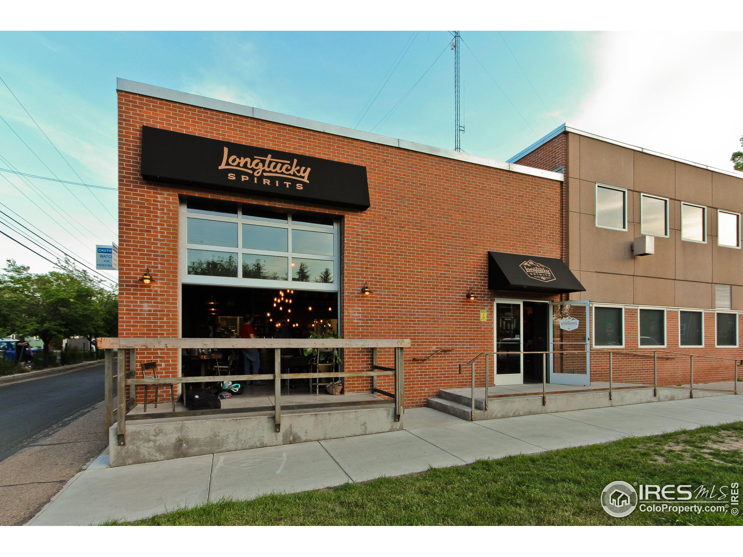 Longtucky Spirits storefront with a red-brick facade, large windows, and a raised outdoor deck.