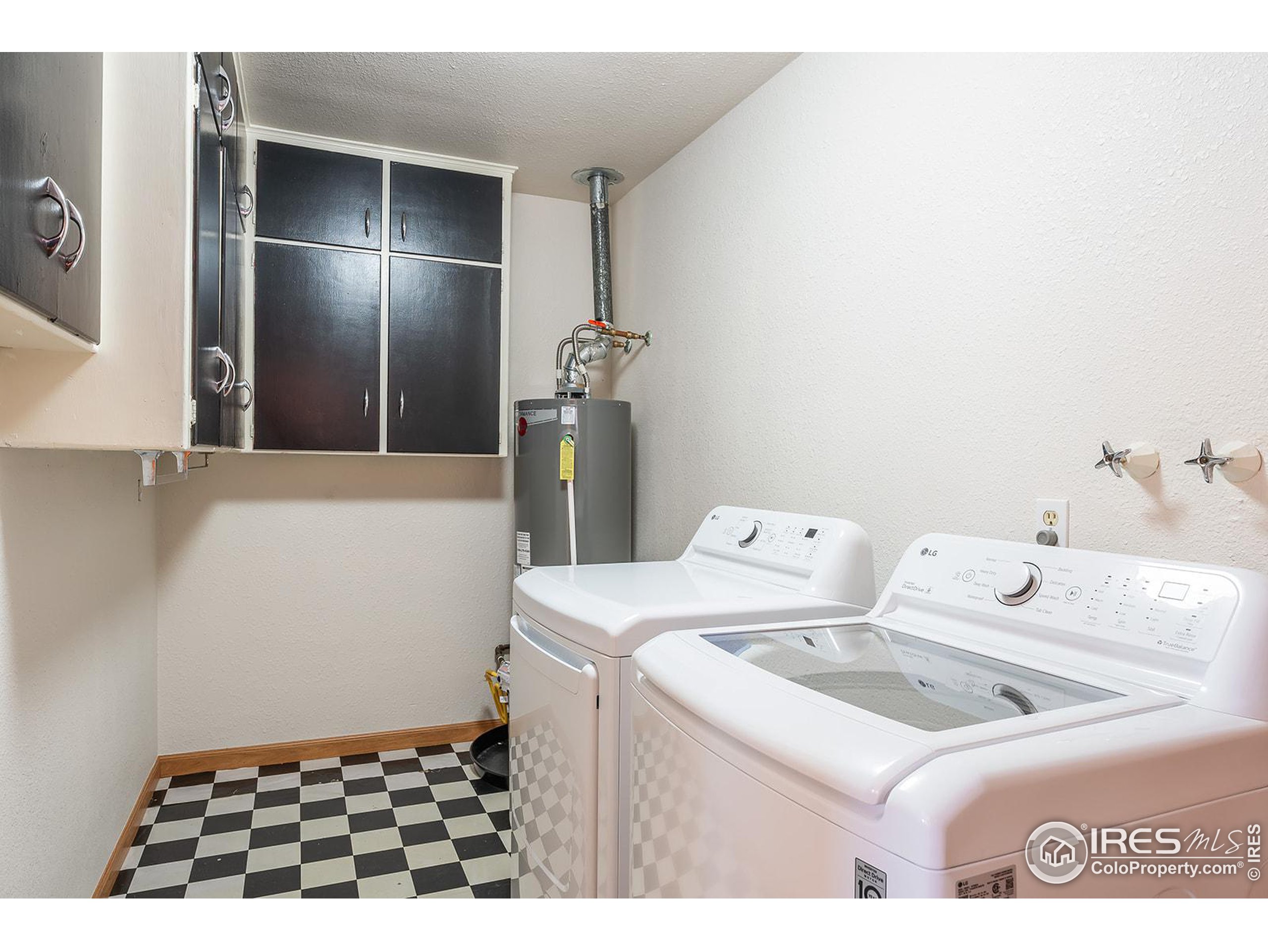 Laundry room with white washer and dryer, dark cabinets, and checkerboard flooring.