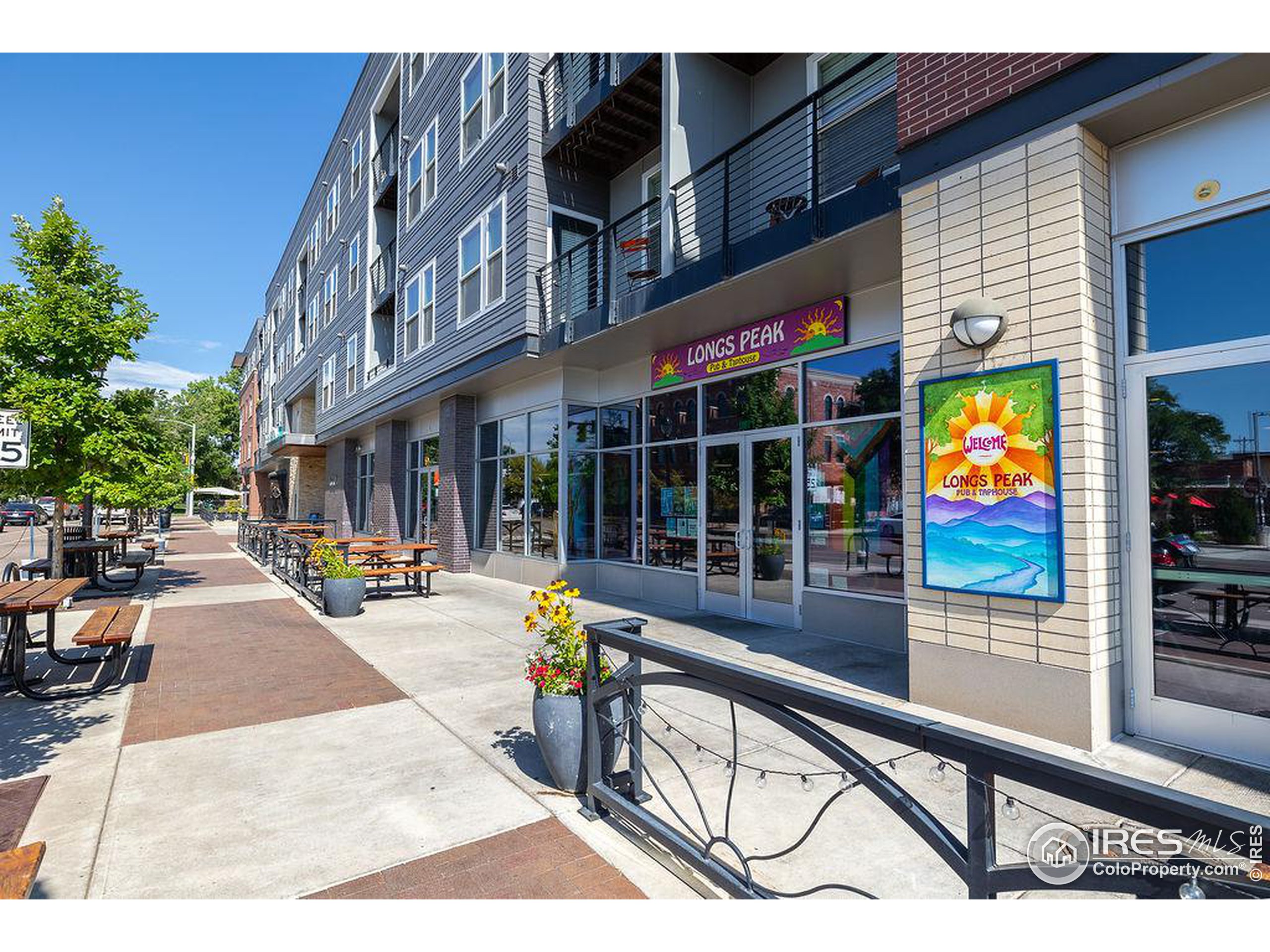 Mixed-use building exterior with Longs Peak Pub & Taphouse storefront and sidewalk seating.