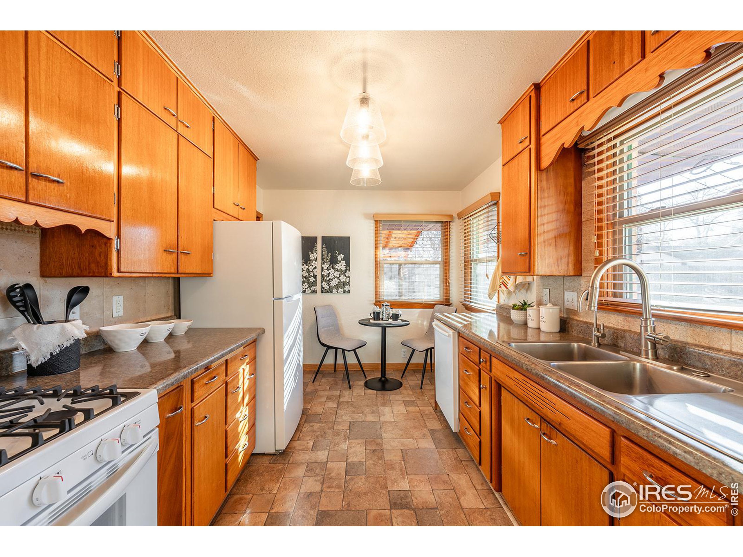 Kitchen with warm wood cabinetry, stone counters, and a small dining nook by the windows.