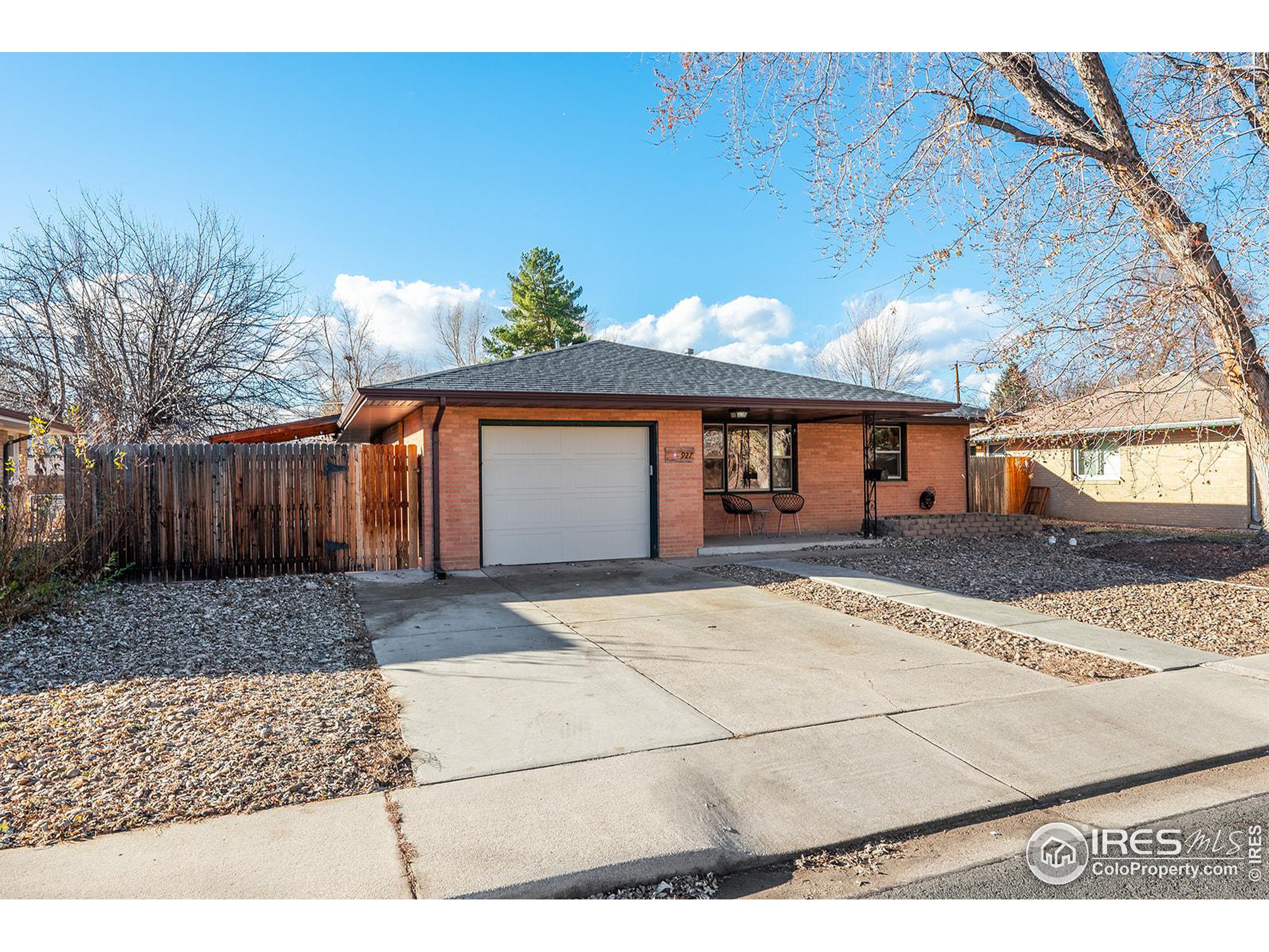 Single-story brick home with an attached garage, wide driveway, and covered porch.