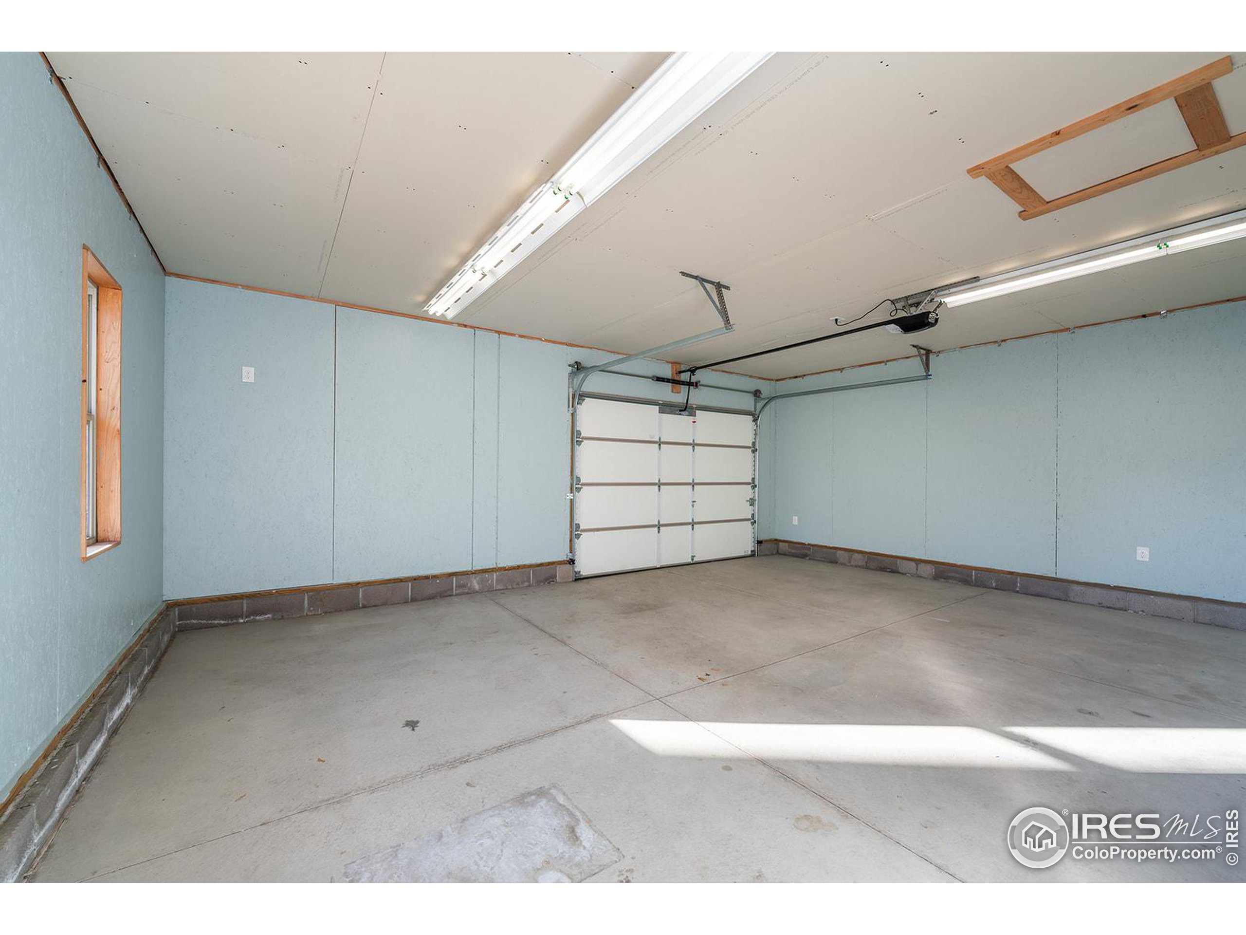 Empty garage with light blue walls, concrete floor, and a closed sectional door.