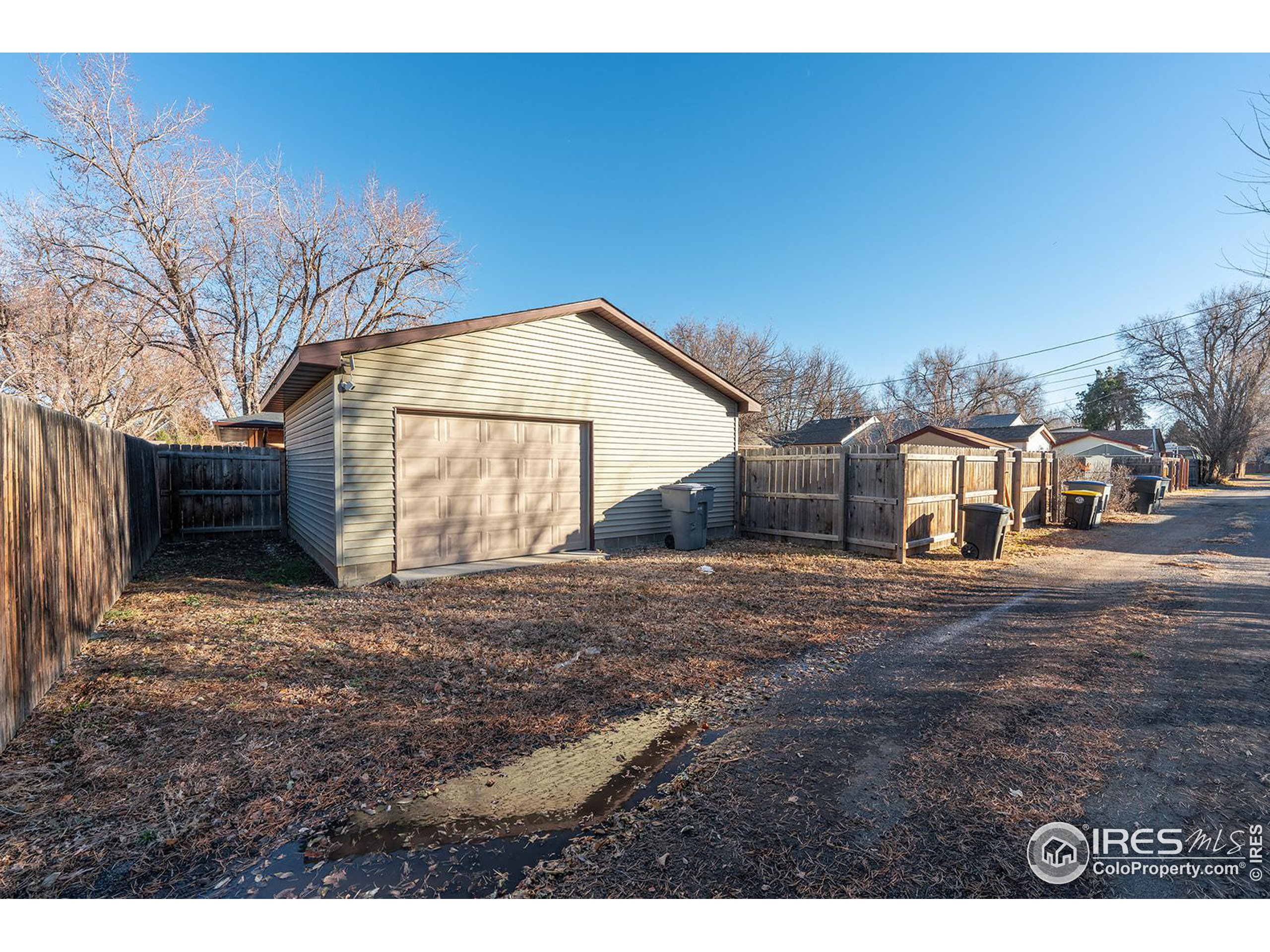 Detached garage with a double-width door, fenced yard, and residential alley.