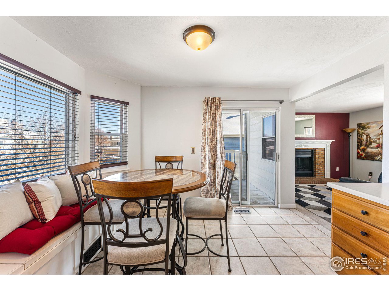 Dining area with a round table, red-cushioned window bench, and sliding glass doors to a patio.