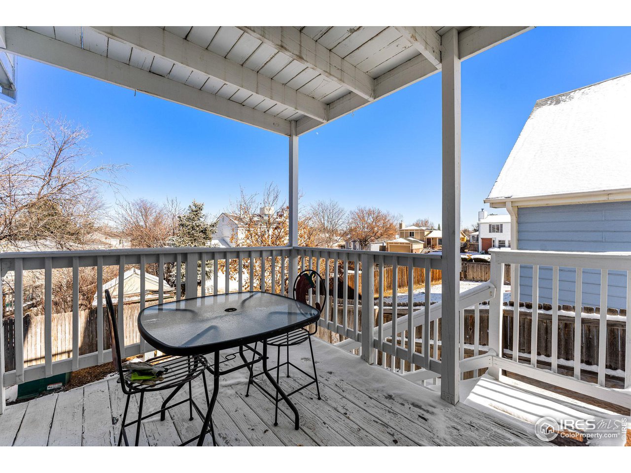Covered back deck with patio table and chairs overlooking snowy neighboring yards.